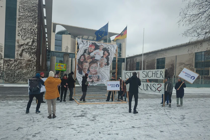 Around a dozen AI safety protesters standing before a government building in Berlin